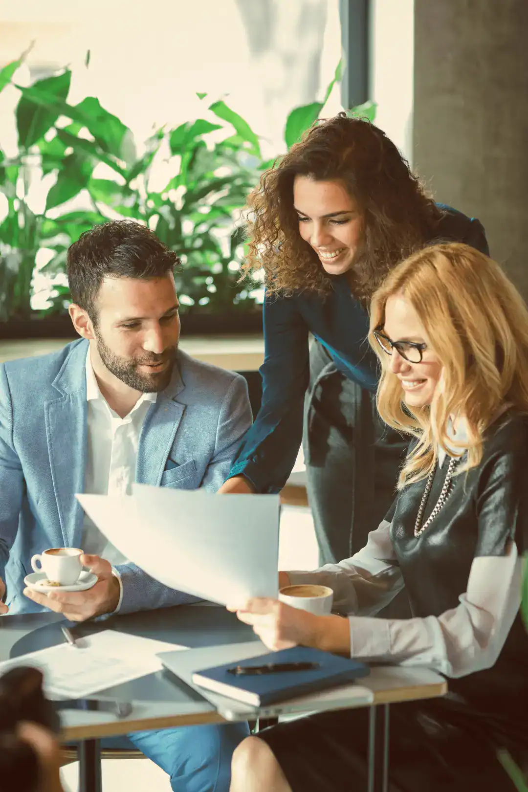 Business team reviewing documents over coffee; digital marketing strategy session.