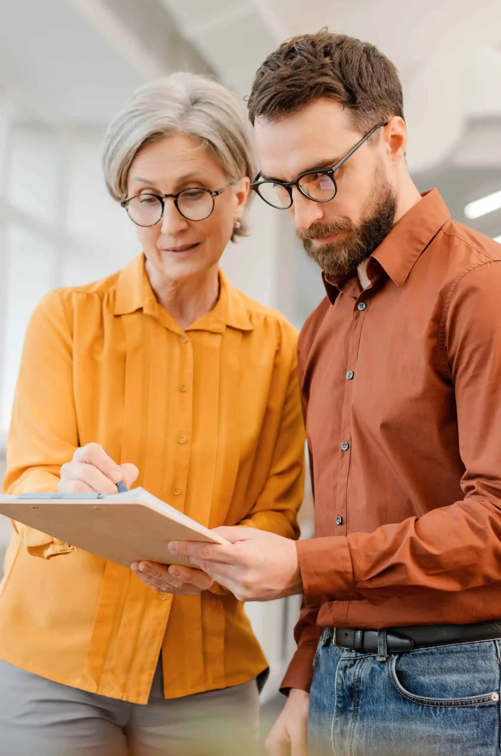 Two strategists reviewing a clipboard, symbolizing iBrandStrategist’s data-driven marketing.