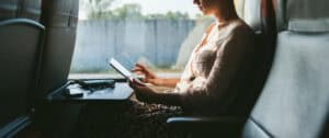 A woman uses a tablet while sitting by the window during a train commute.