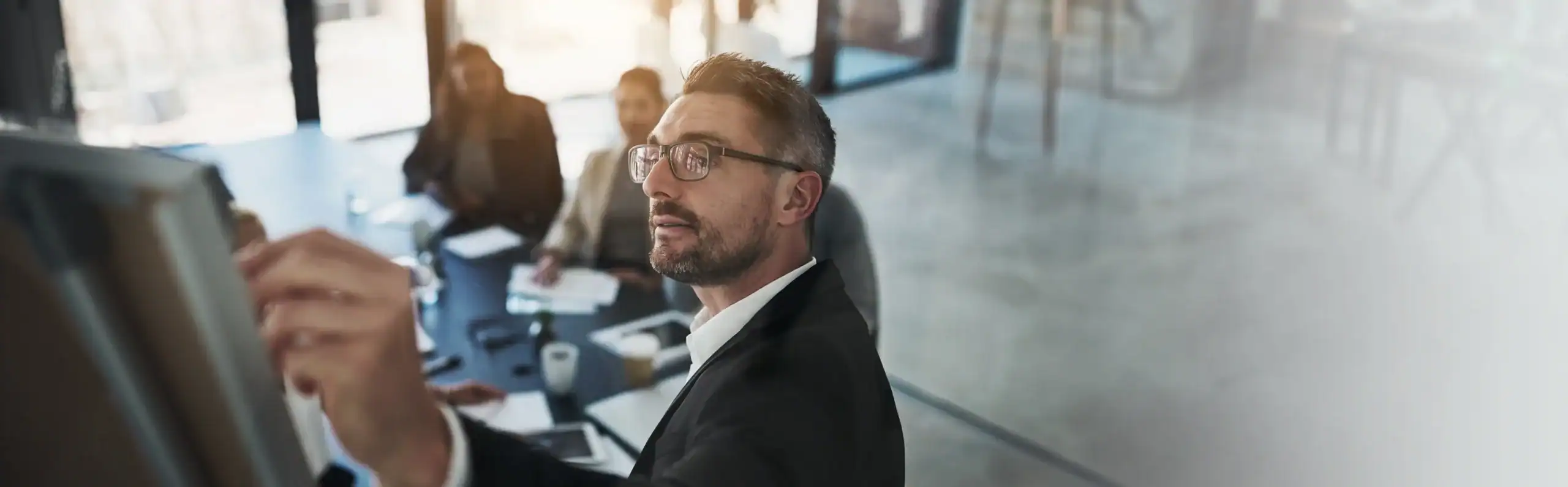 Businessman writing on whiteboard during corporate meeting with team.