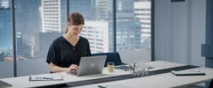 Professional woman working on a laptop in a modern corporate office overlooking the city skyline